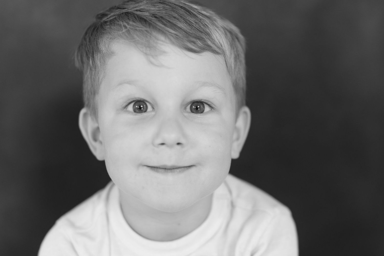 A series of black and white close-up photos showing the changing expressions of a young child.