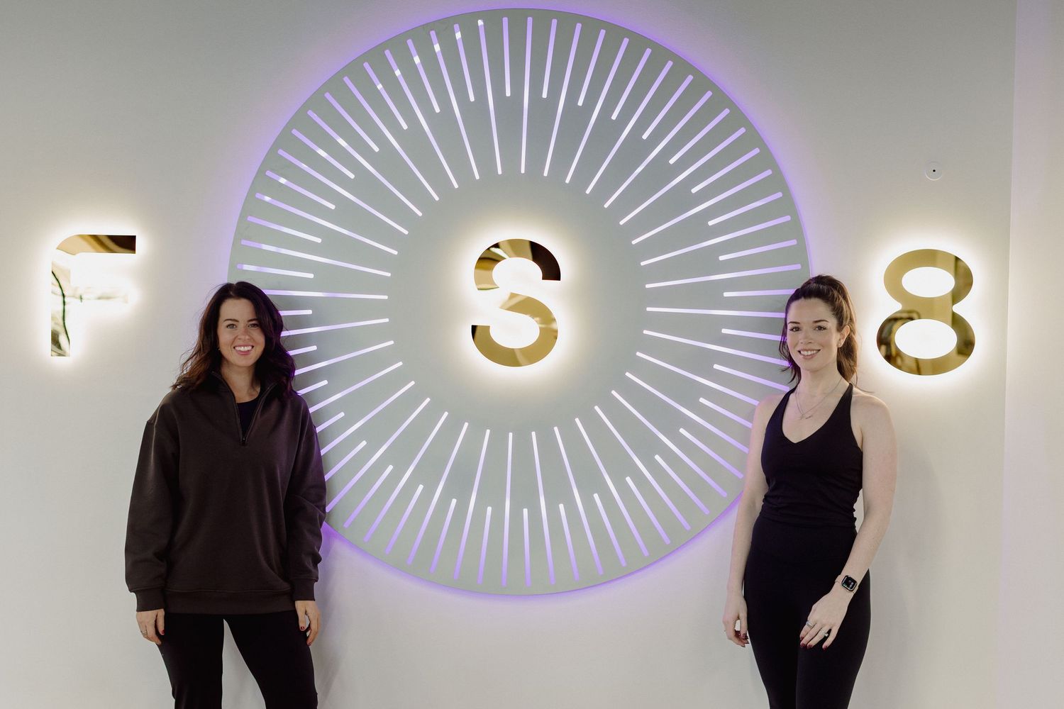 Modern fitness studio interior with illuminated eye-shaped wall decorations and minimalist design elements.