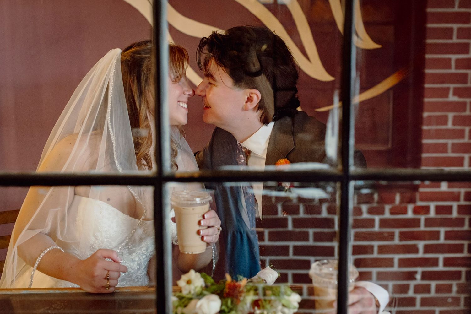 A romantic wedding couple shares an intimate moment in front of a rustic brick wall during their reception.