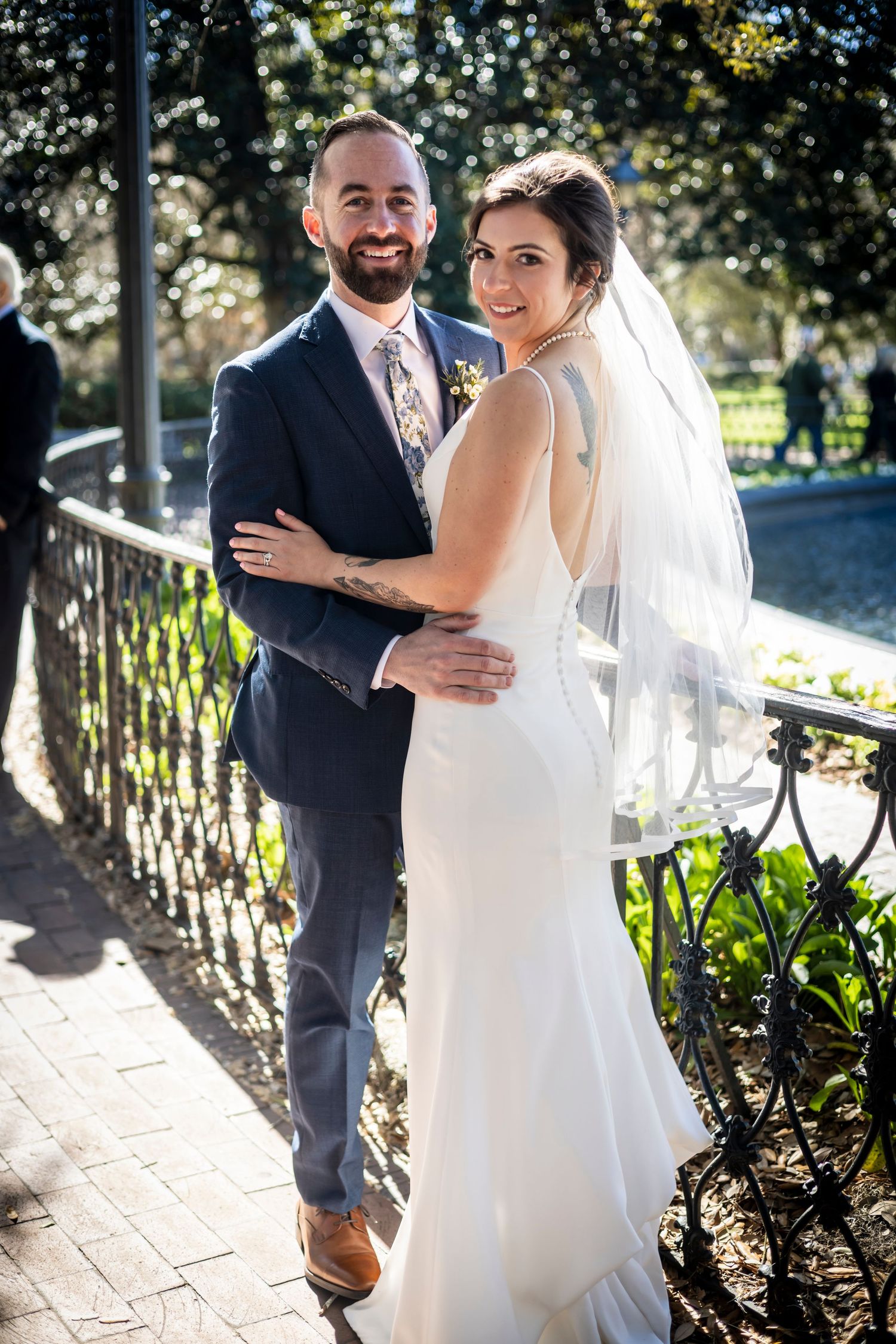 Sunlit outdoor wedding portraits taken along garden pathway.