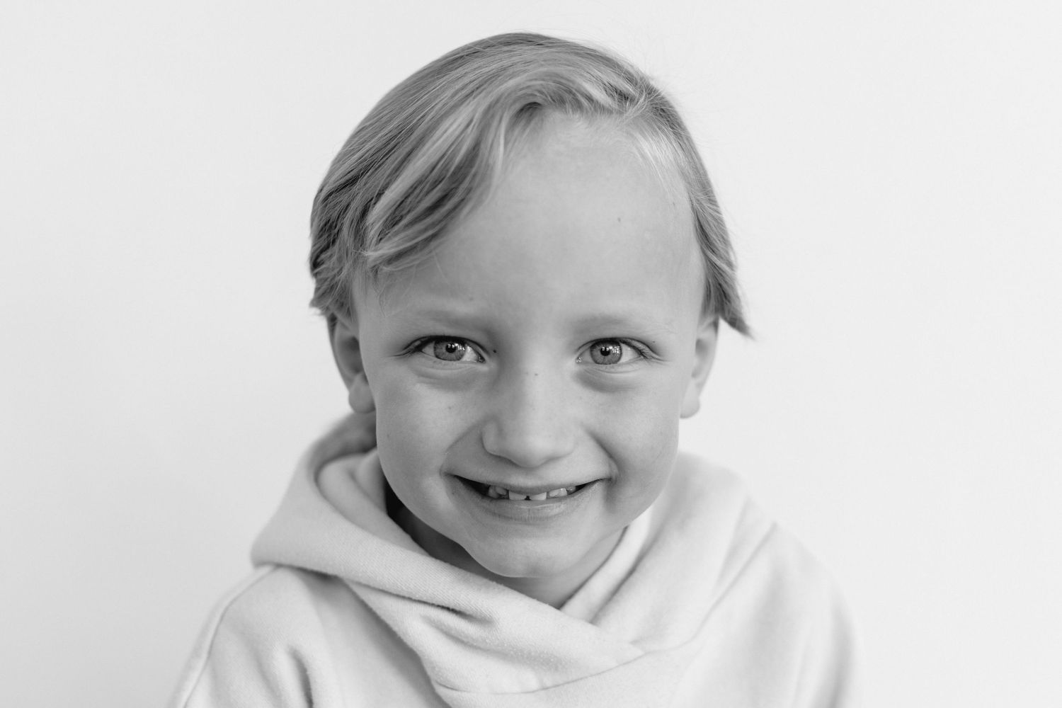 Three black and white portraits of a child with blonde hair wearing a white shirt against a light background.