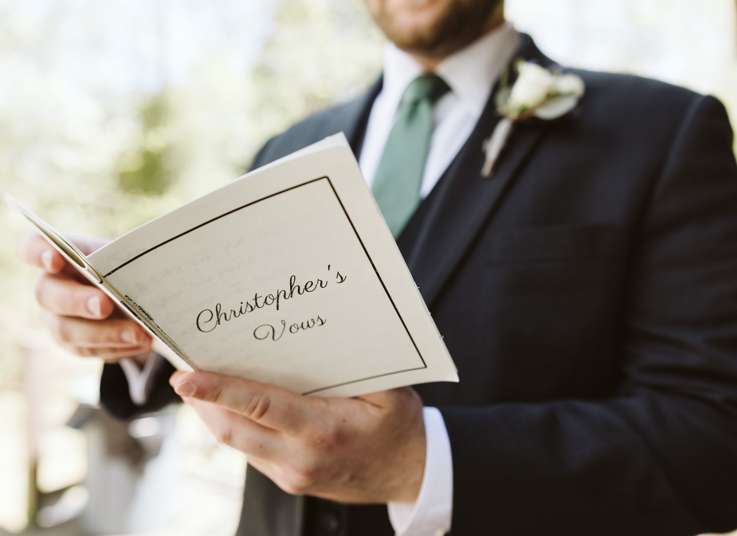 Close-up of hands holding wedding ceremony program or invitation cards.