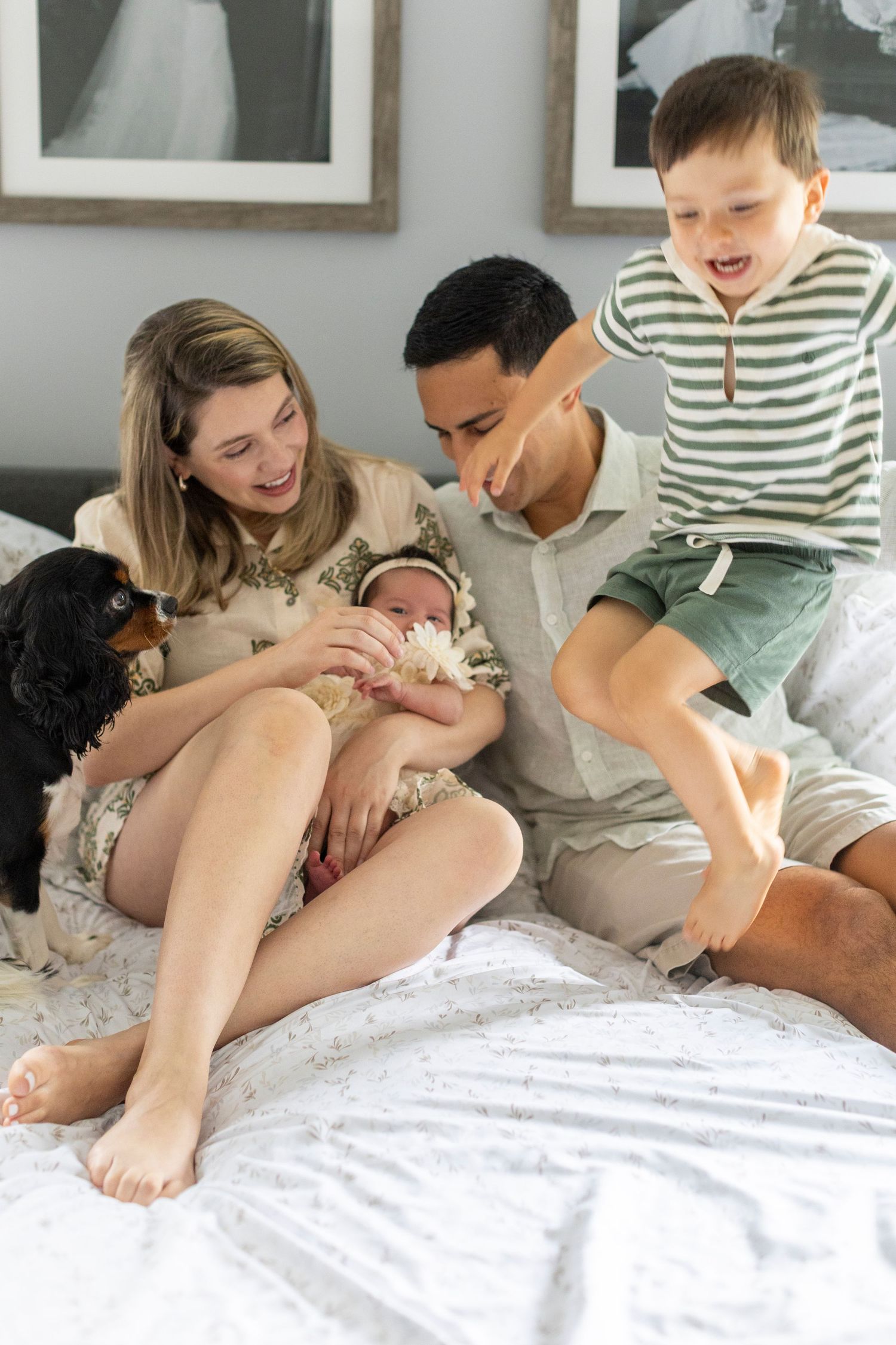 A family relaxes together on a white bed with their small dog, sharing tender moments of connection and joy.