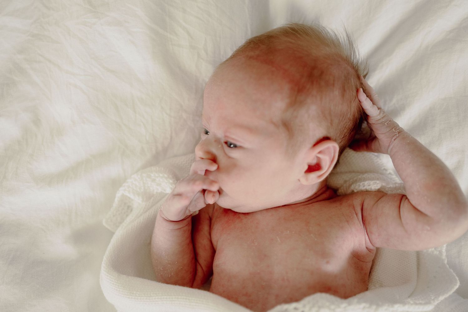 A sleeping baby lies peacefully on white bedding in a series of connected photos showing different angles and positions.