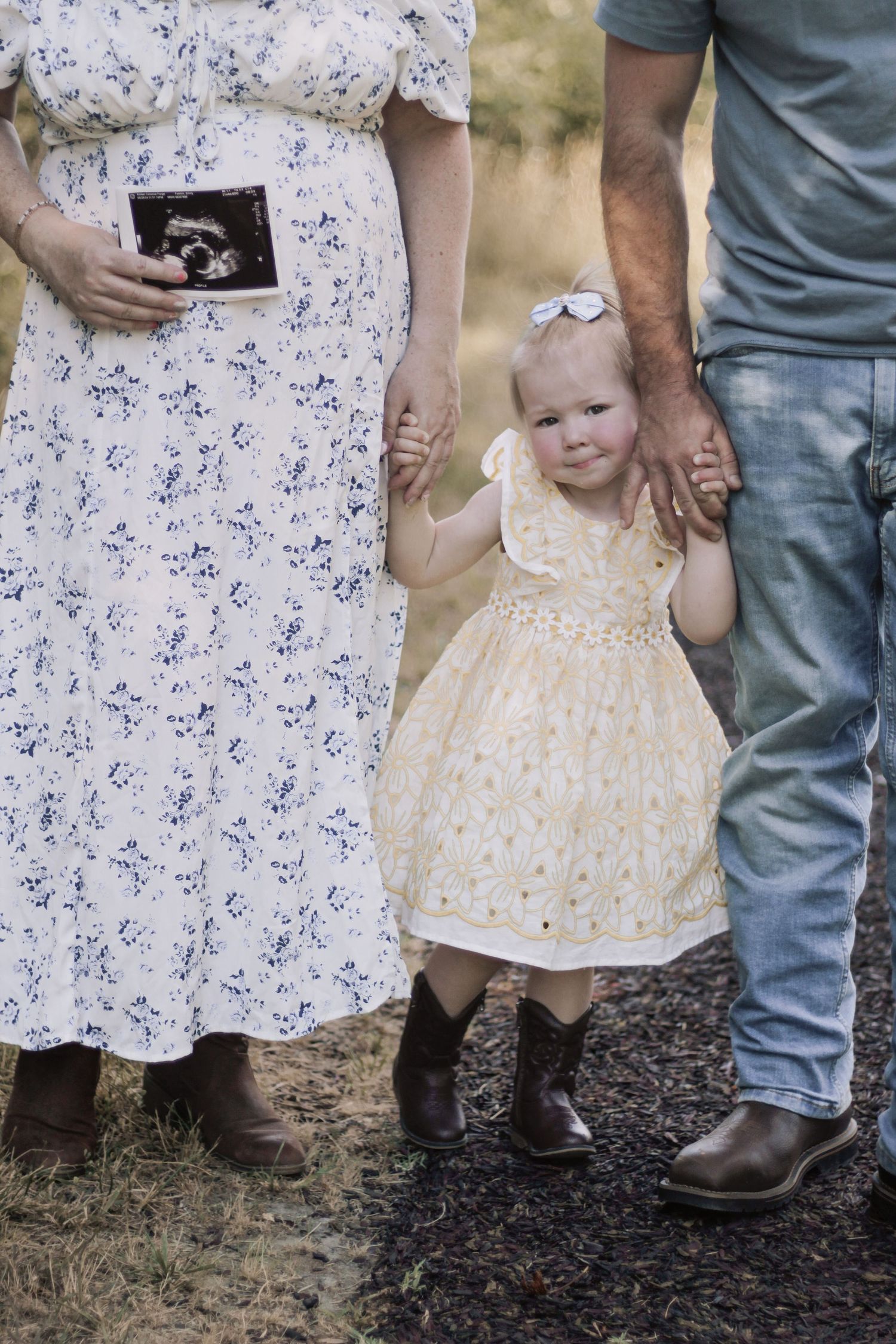 A floral dress and blue jeans are shown in close-up against a natural outdoor background.