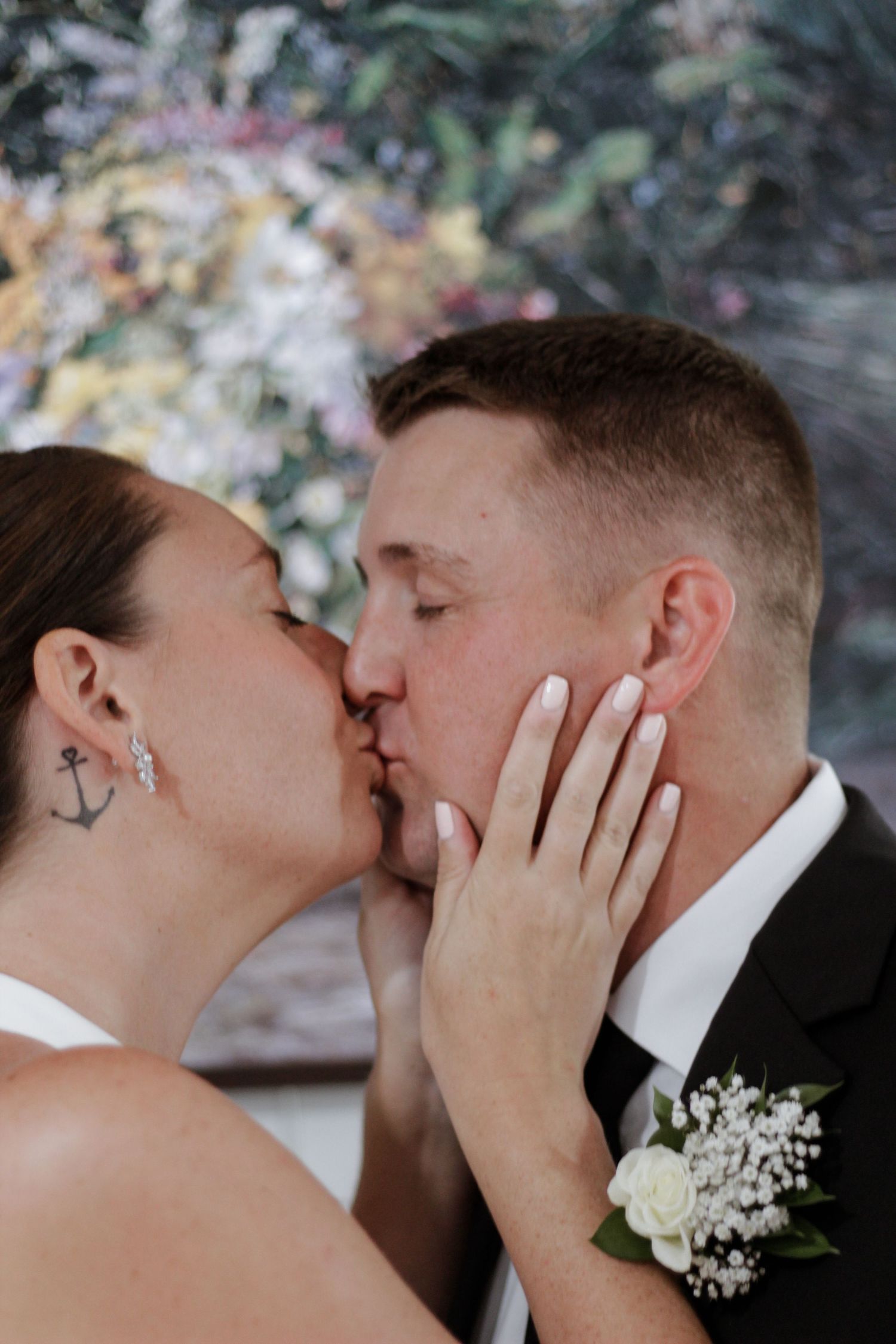 Intimate wedding kiss captured with baby's breath boutonniere detail.
