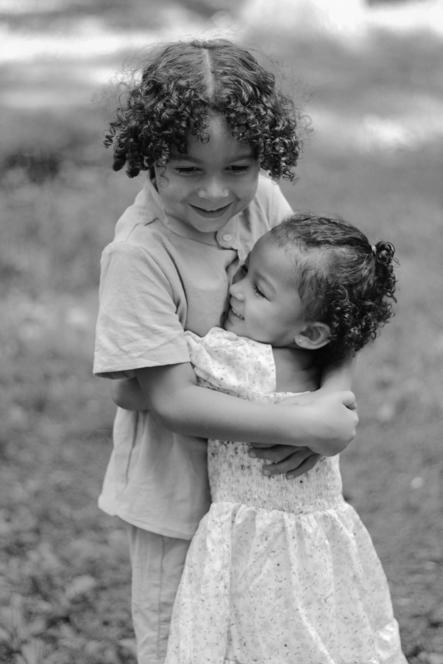 Heartwarming black and white photo sequence showing two children sharing an affectionate moment in an outdoor setting.