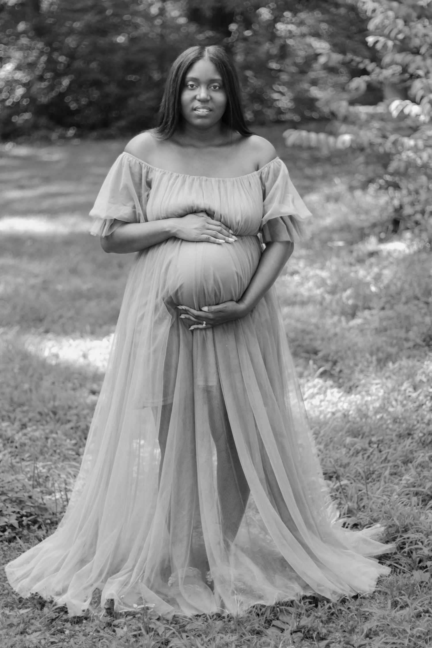 A flowing tulle maternity dress is showcased in a series of black and white outdoor photos with a natural garden backdrop.