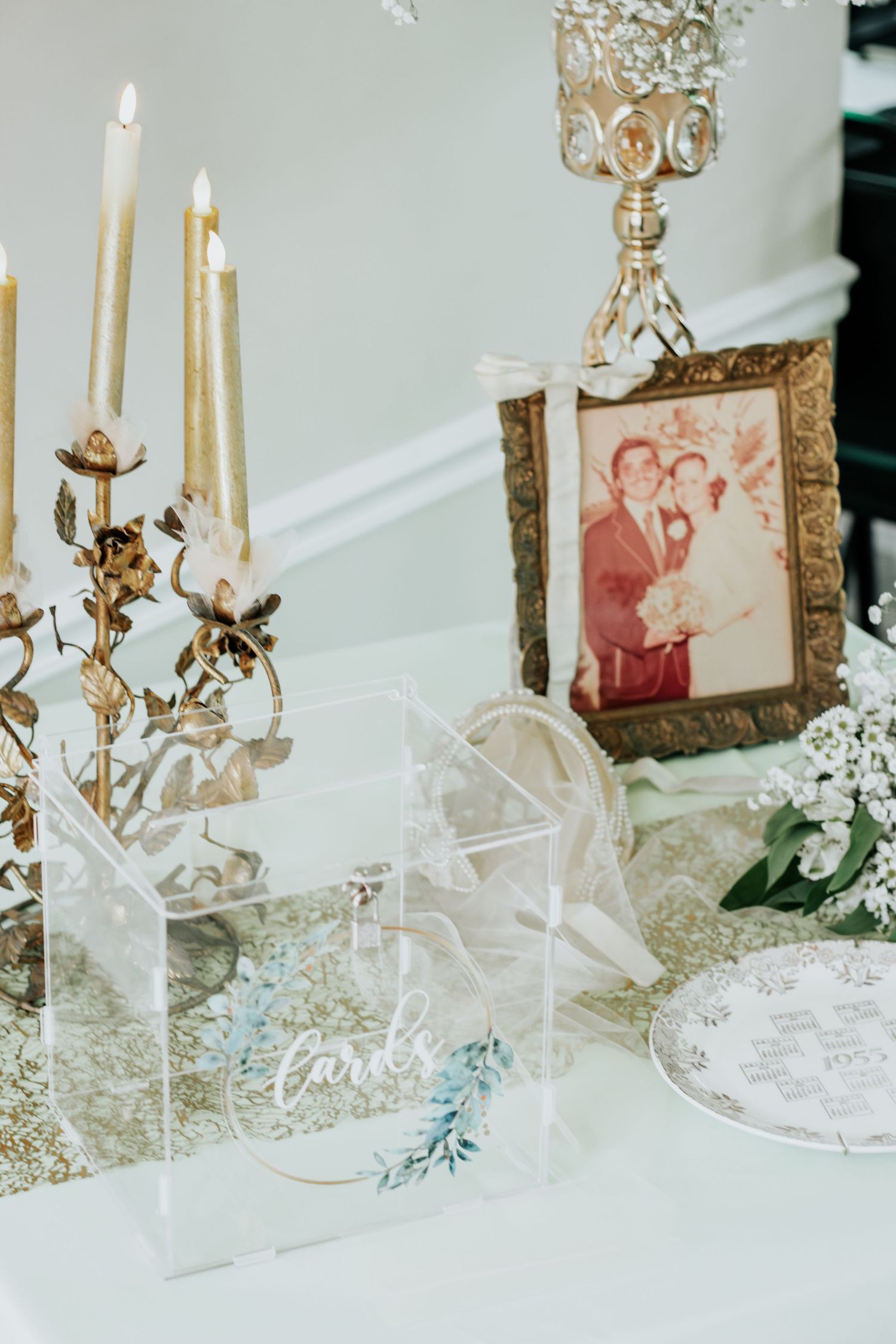 Wedding decor display with white candles, decorative frames and delicate floral accents.