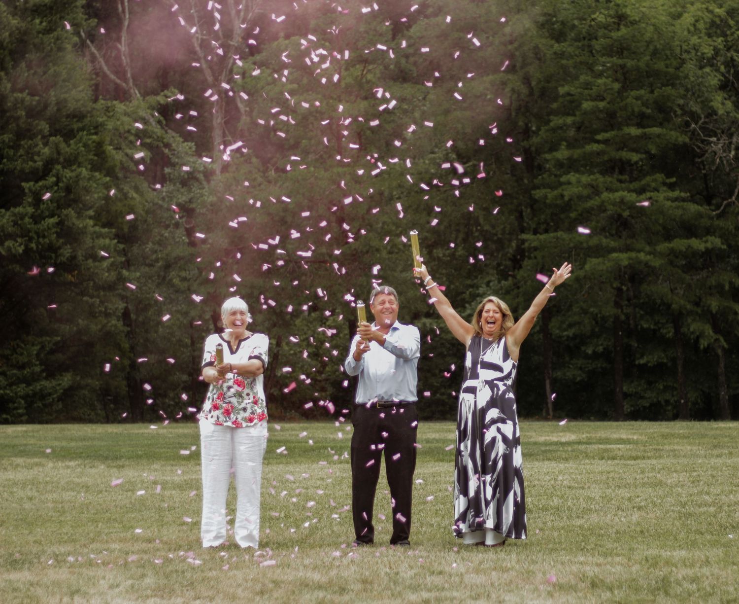 Wedding celebration with pink confetti being tossed in an outdoor garden setting.