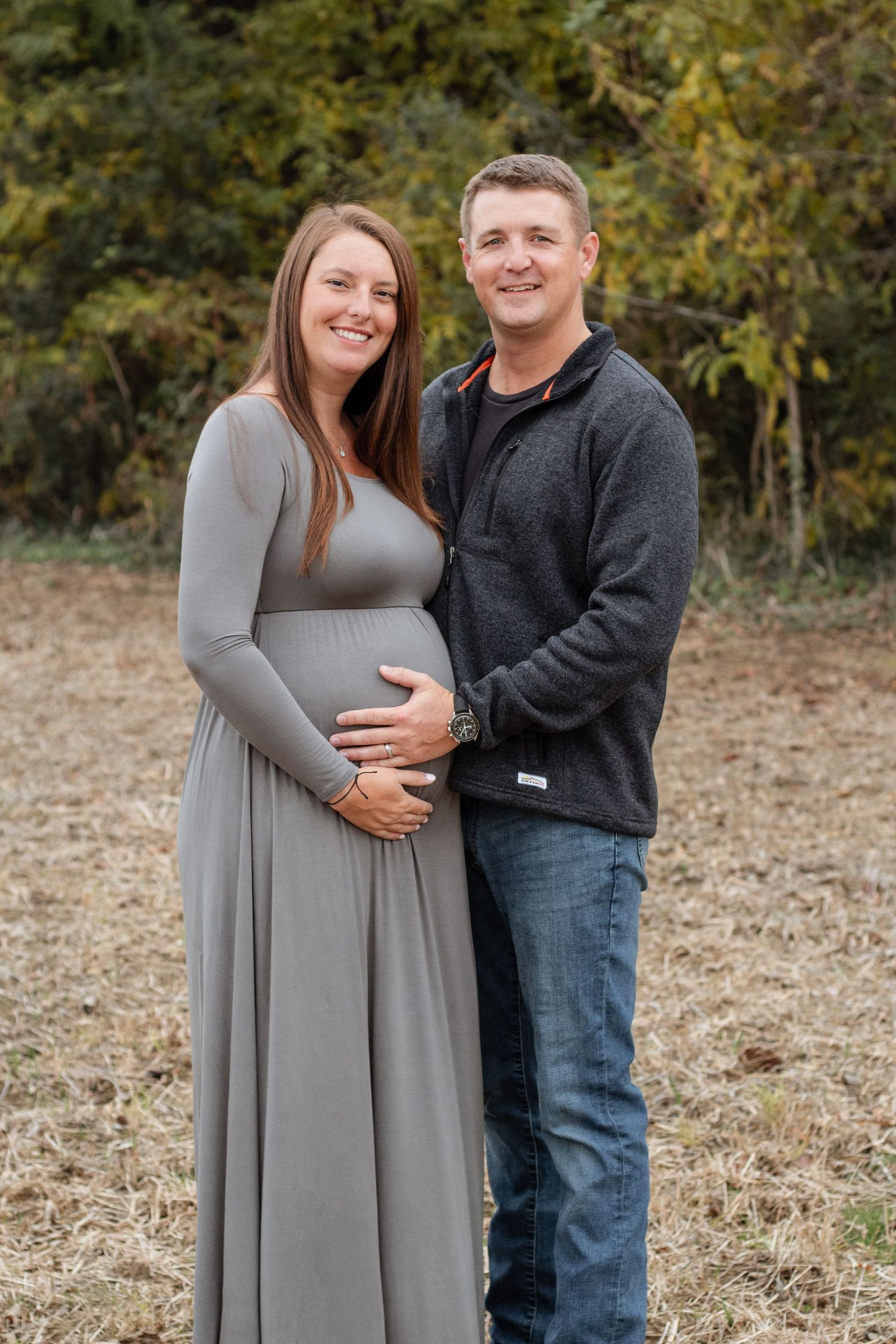 Couple poses together for outdoor maternity photos in casual fall attire.