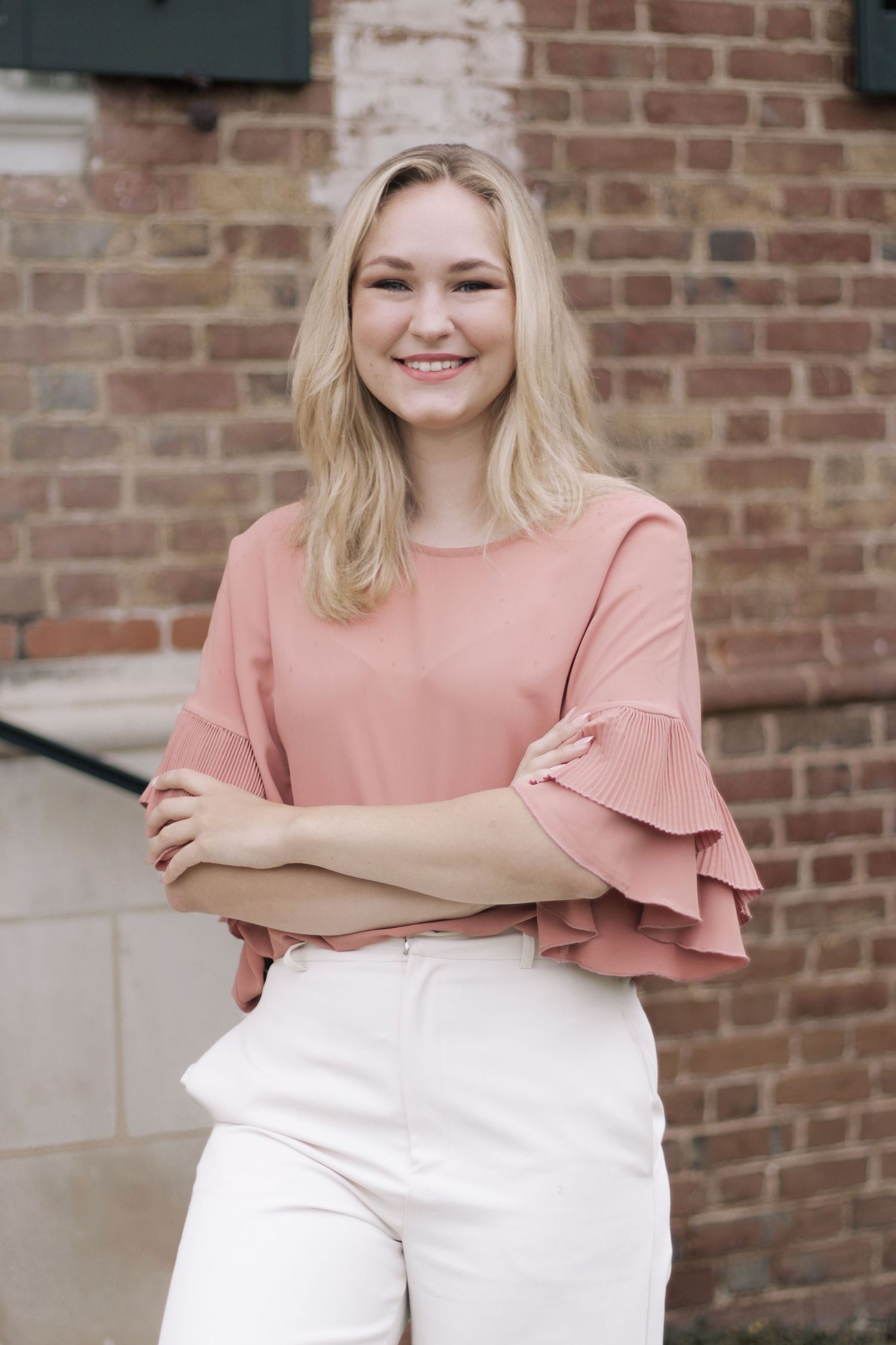 Portrait series showing casual pink and white outfit against brick background.