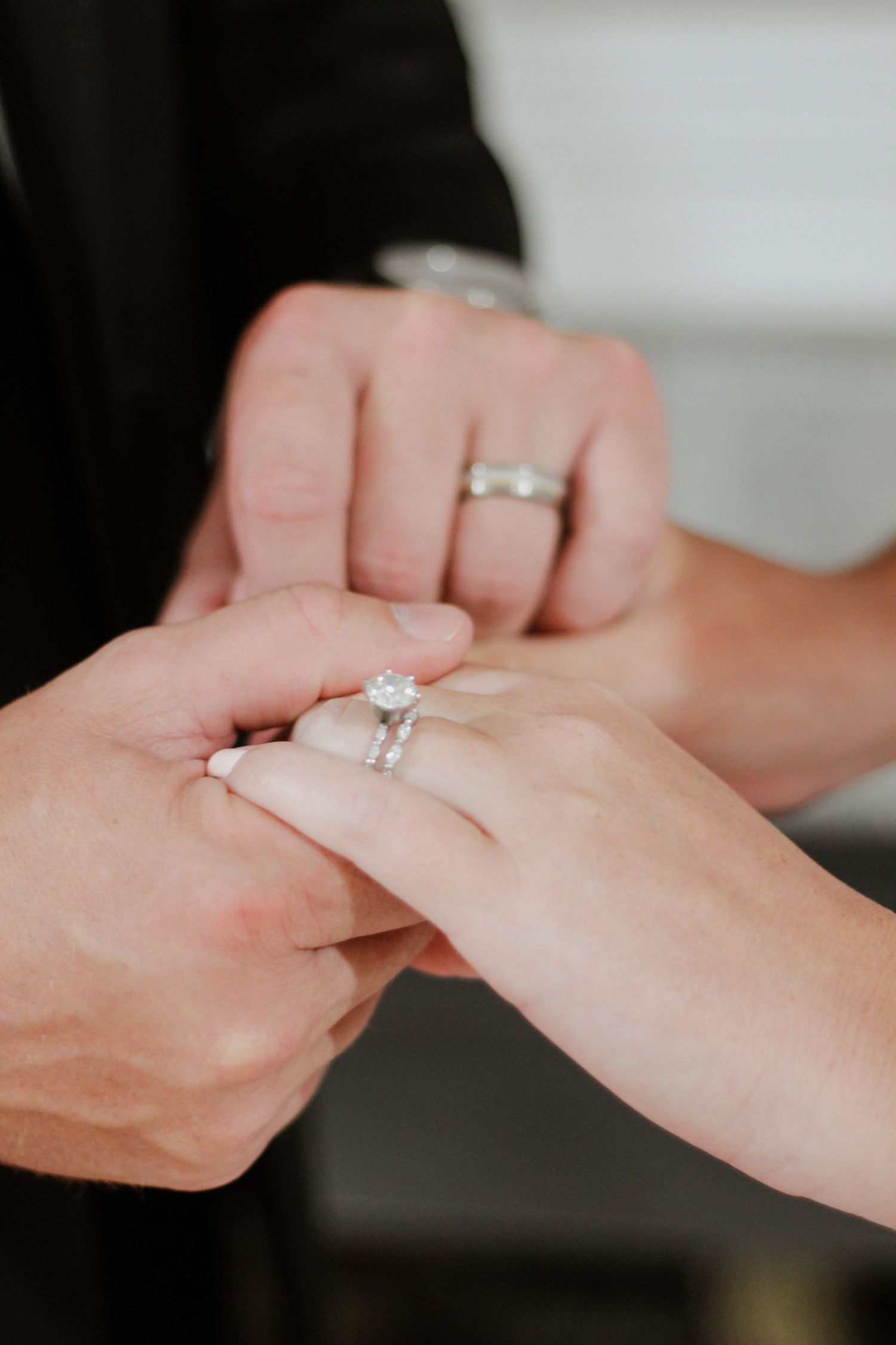 Close-up of hands exchanging diamond engagement ring in romantic moment.
