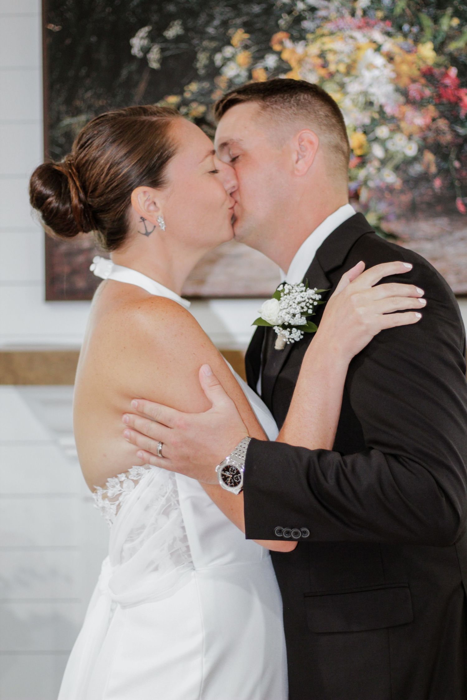 First kiss moment at wedding ceremony against floral backdrop.