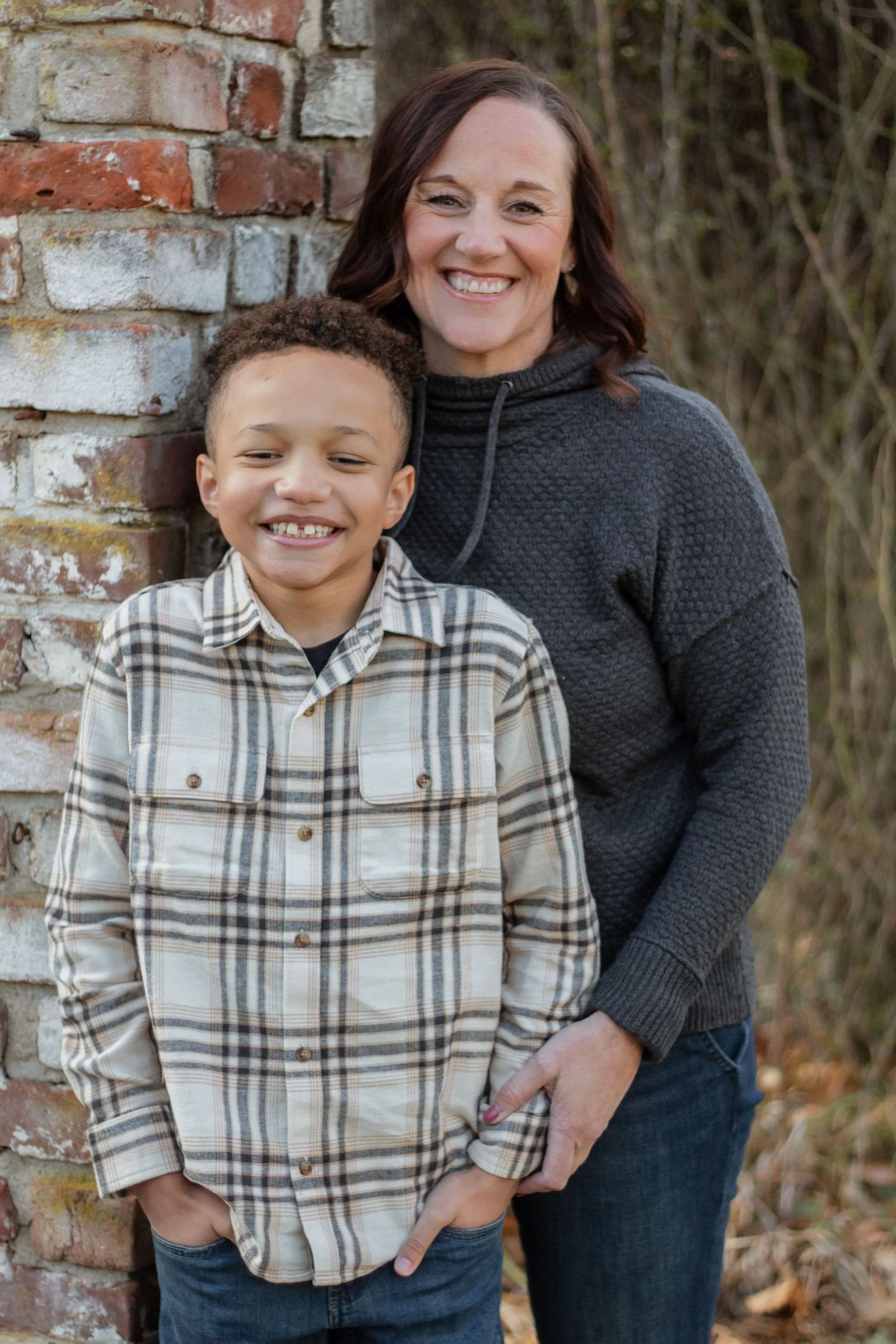 Casual outdoor portrait session against a rustic brick wall.