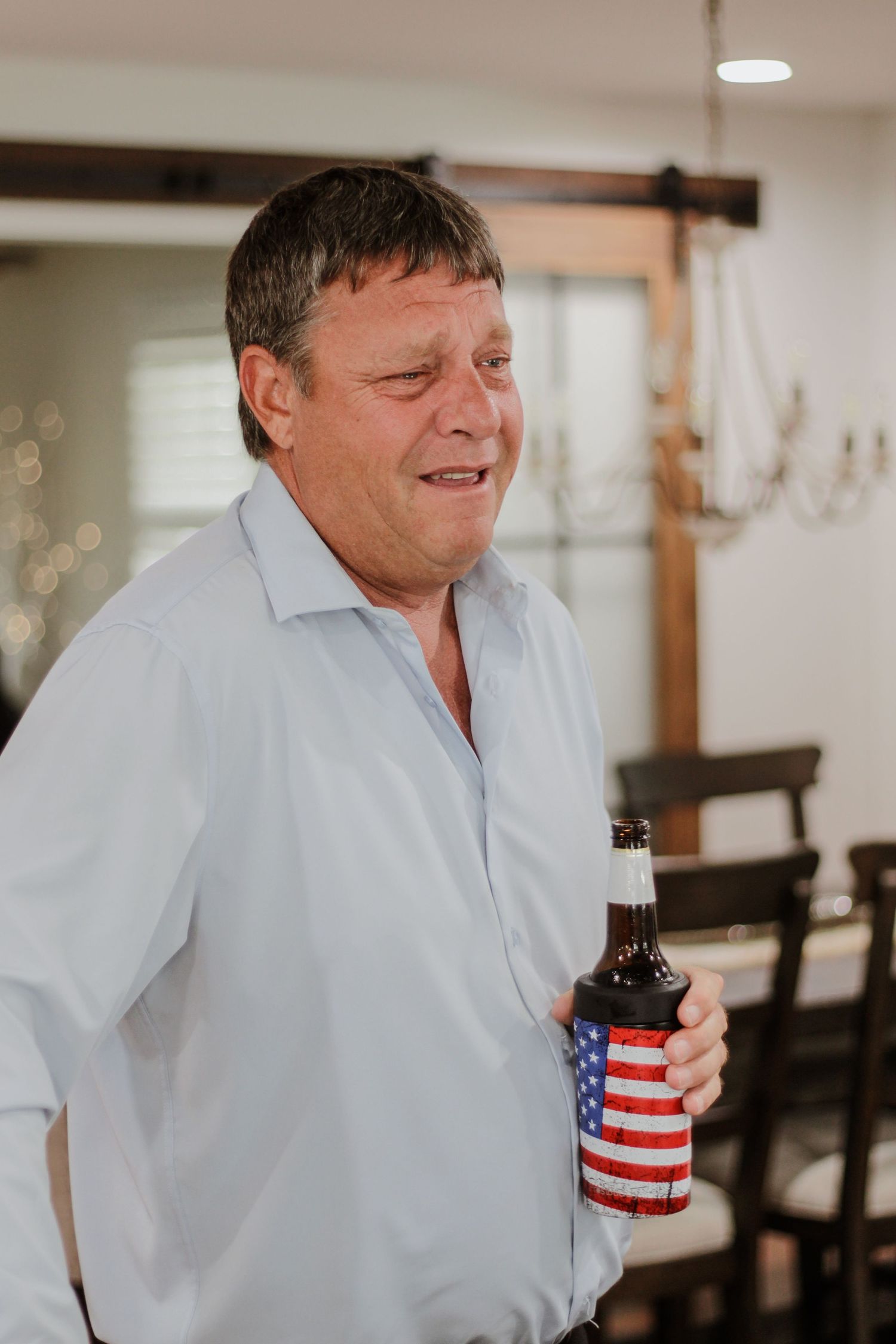 Person in light colored shirt laughing while holding a patriotic themed drink.