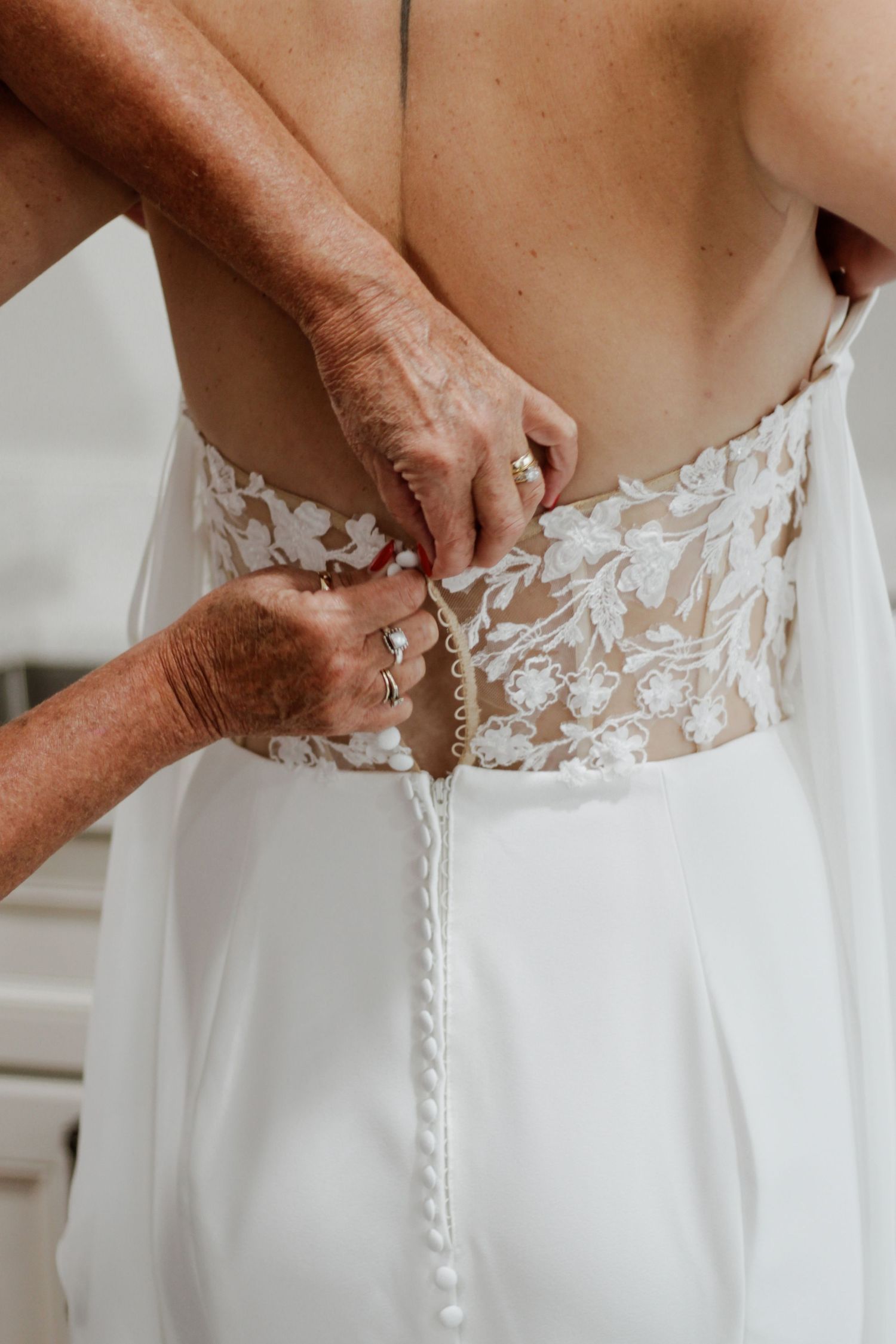 Wedding dress closeup showing intricate lace detailing and buttons along the back.