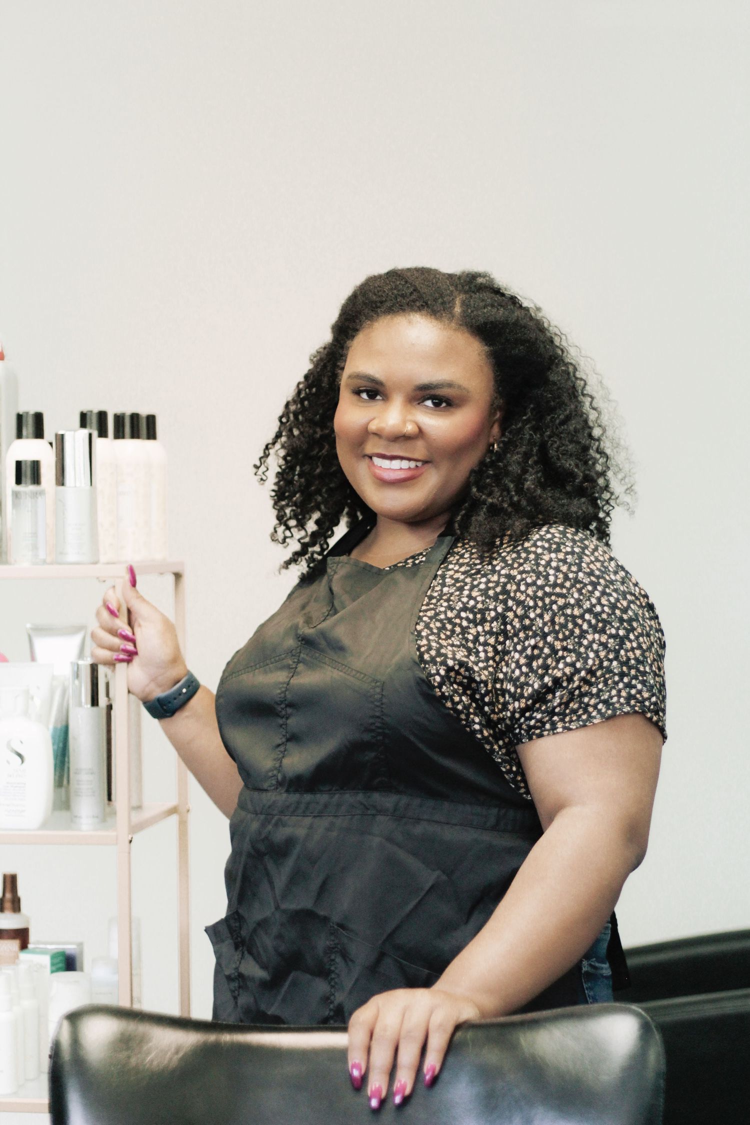 Person in animal print top poses professionally in salon environment with product shelves.