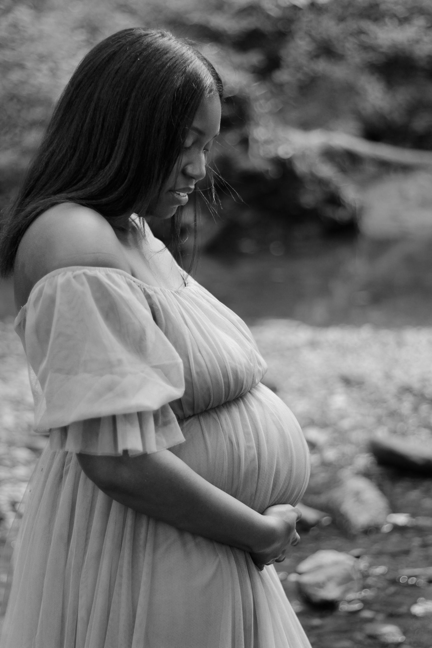 Black and white maternity photo sequence showing a woman in a flowing white dress outdoors.