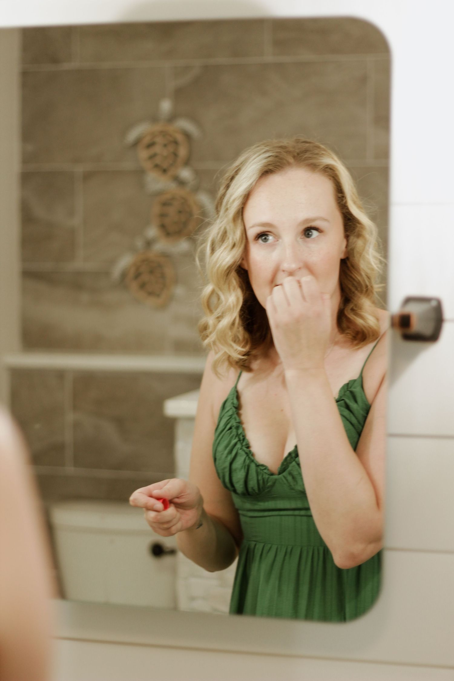 A candid mirror reflection of someone in an emerald green dress showing excitement.