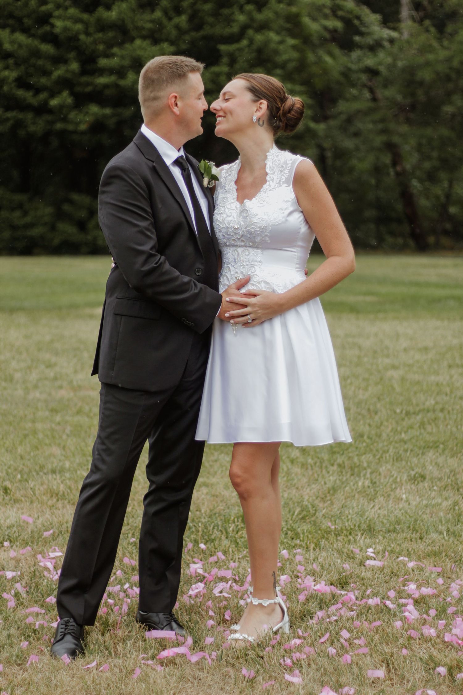 Romantic wedding photos taken in a field with blooming pink flowers.