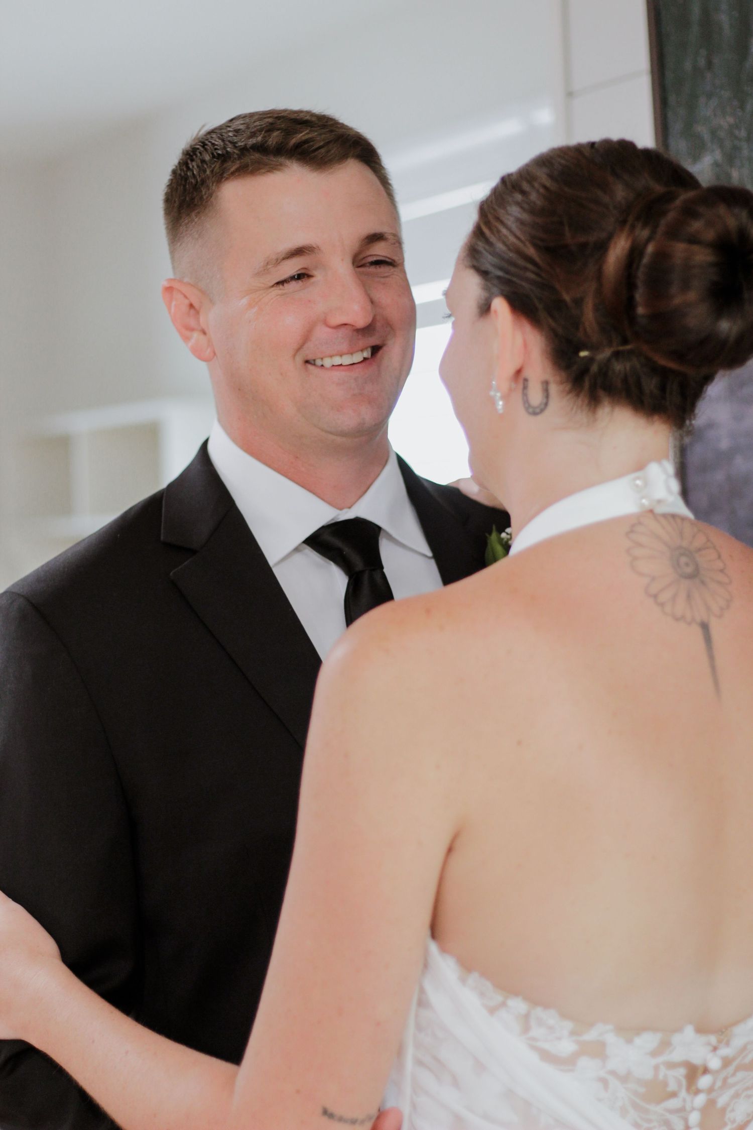 Tender wedding moment captured between couple in classic black and white attire.