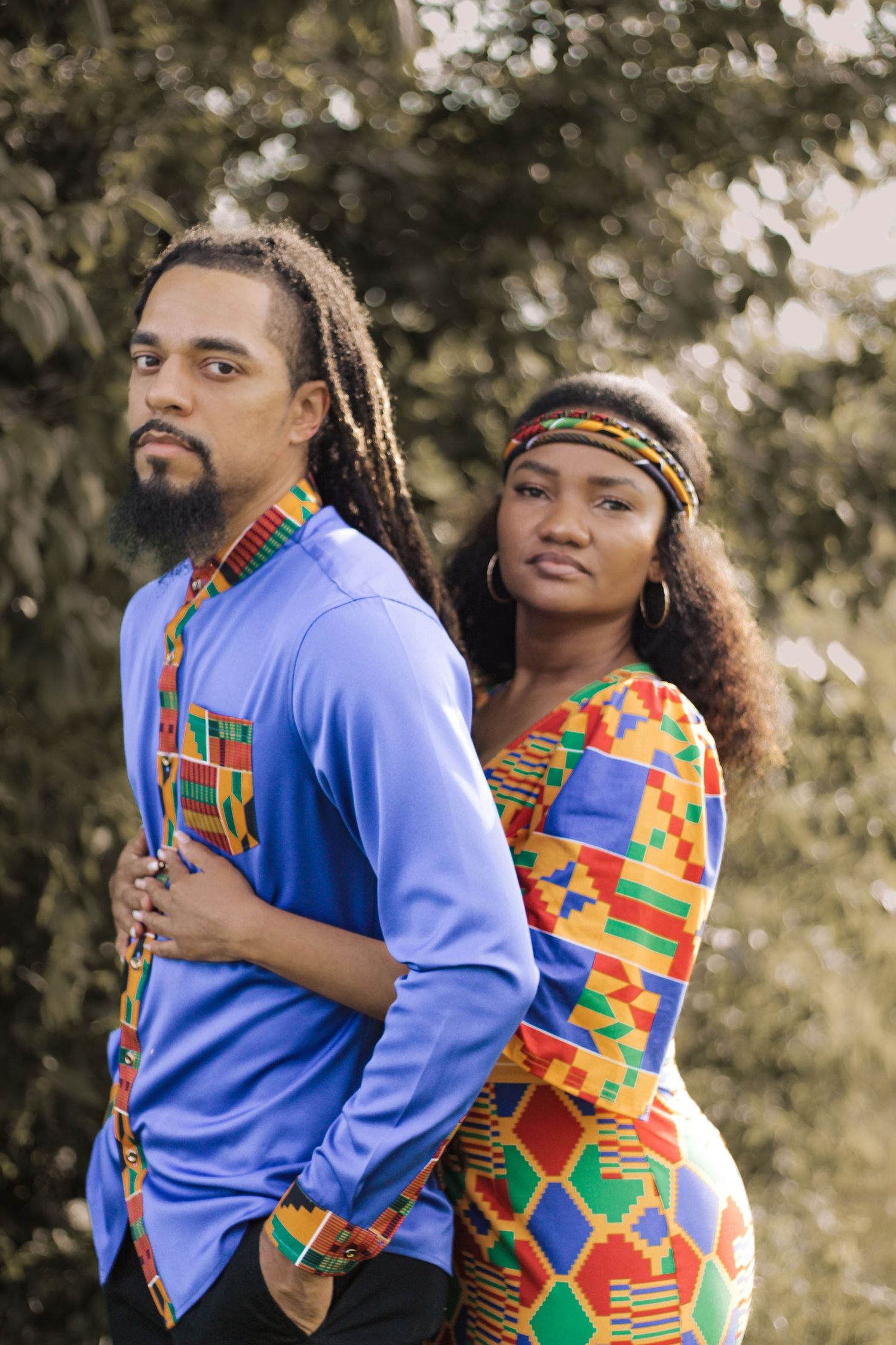 A couple in matching African-inspired blue and colorful print clothing pose together.