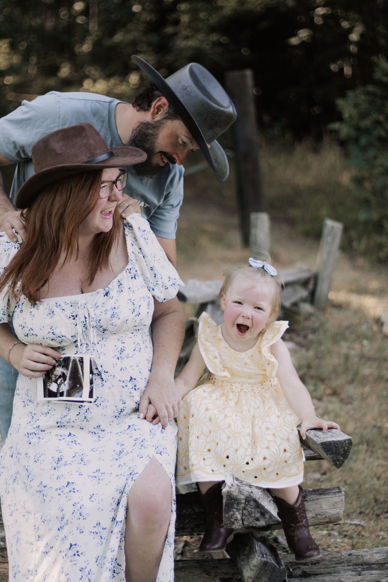 Happy family moment captured on rustic fence with ultrasound photo and yellow dress.