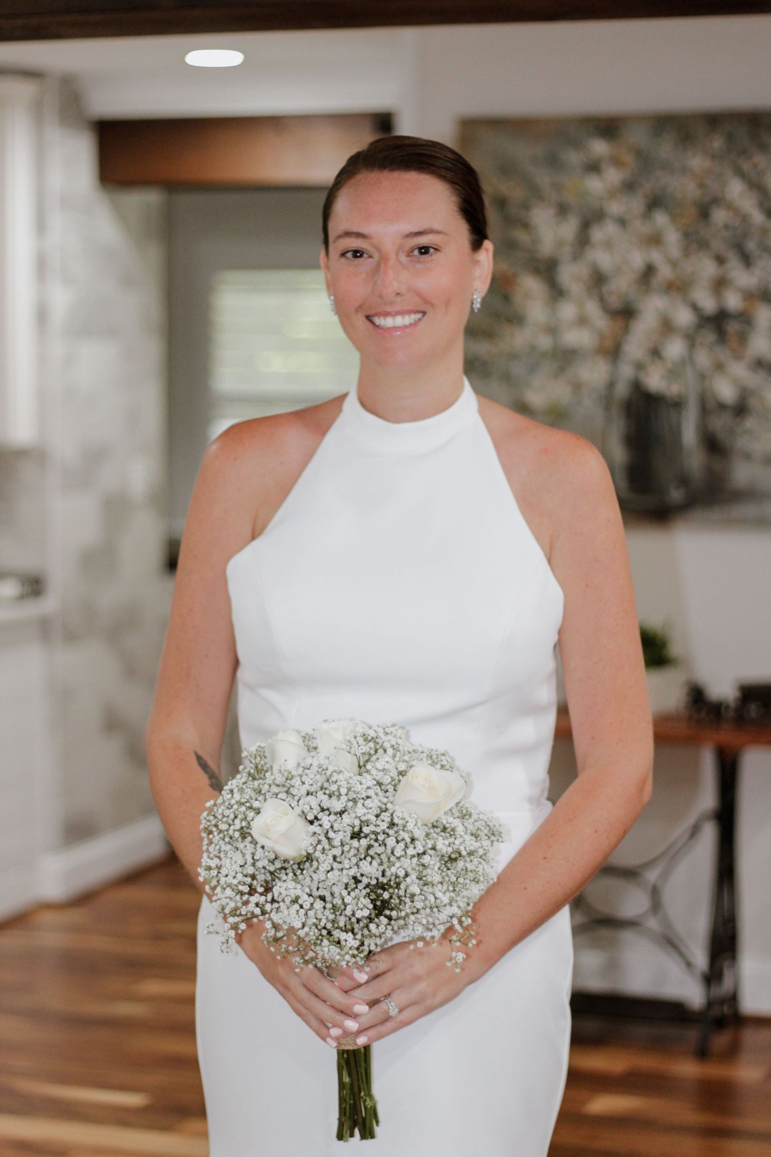 Elegant bride in a high-neck white wedding dress holds a baby's breath bouquet.