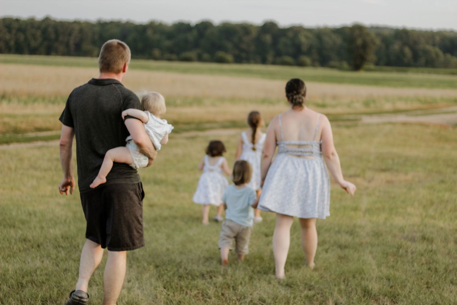 Family walking together through a sunny field during golden hour.