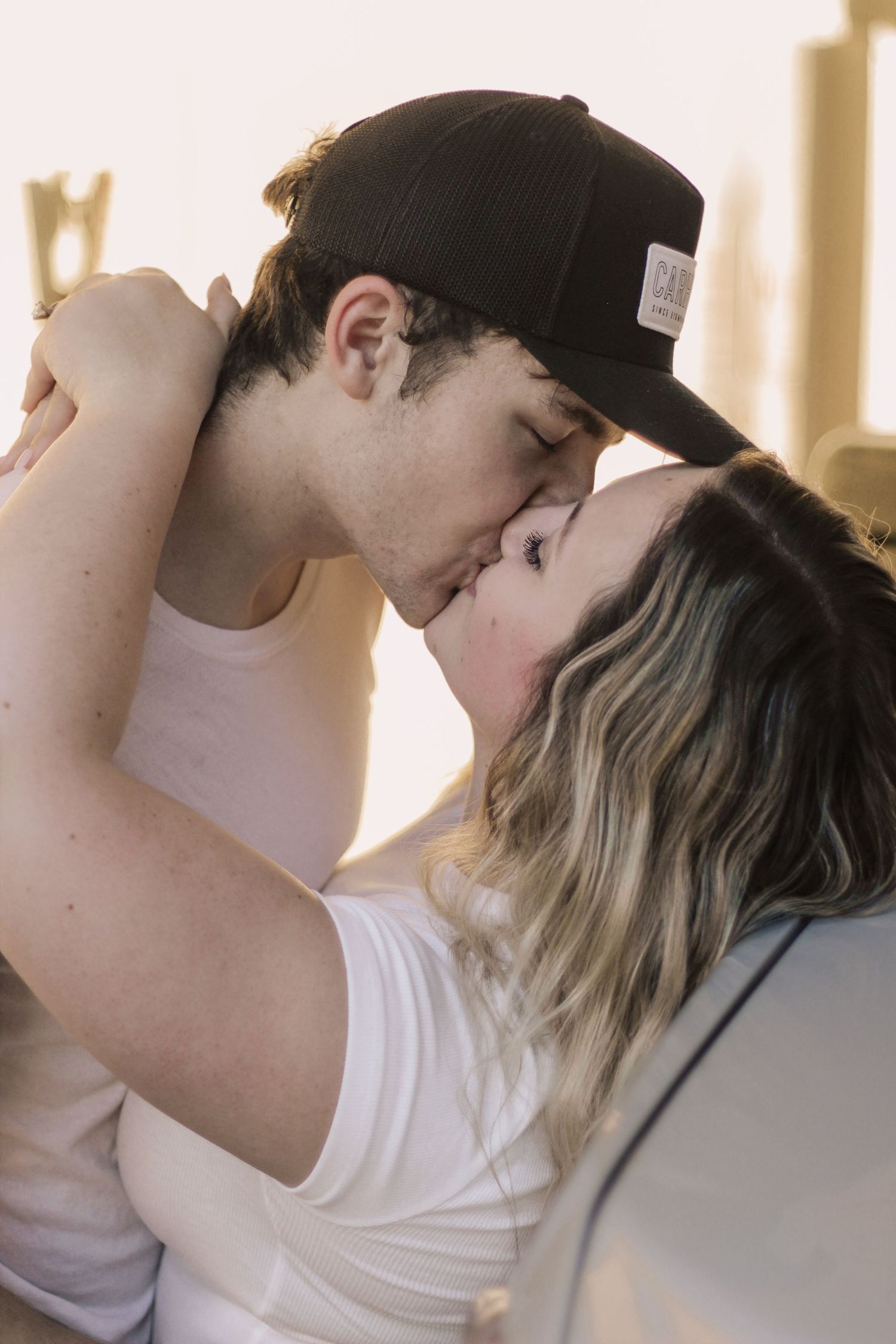 Romantic couple shares tender moments in soft window light.