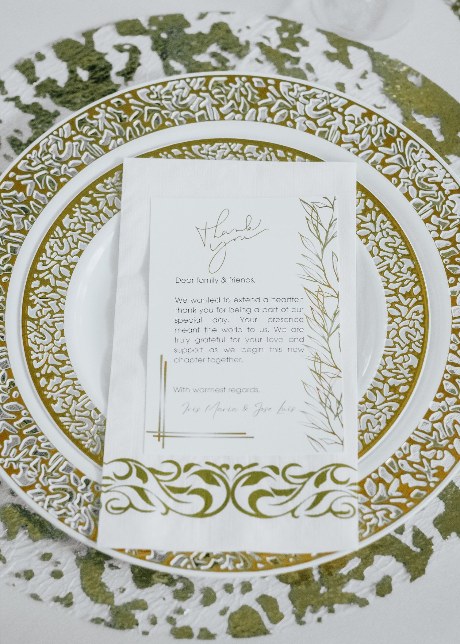 Elegant wedding place setting with ornate gold-rimmed plate and botanical invitation card.