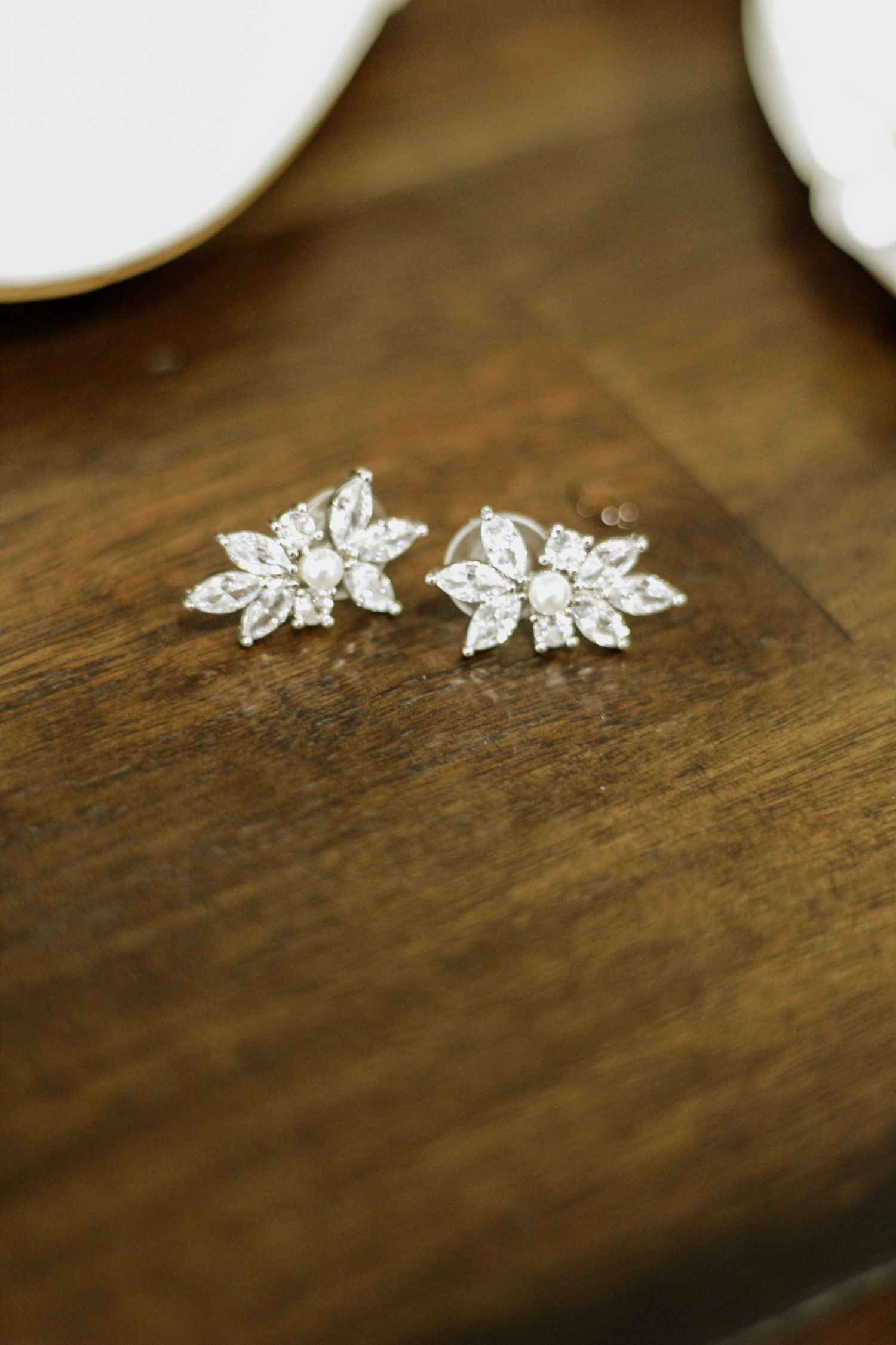 Crystal flower-shaped stud earrings displayed on a wooden surface.