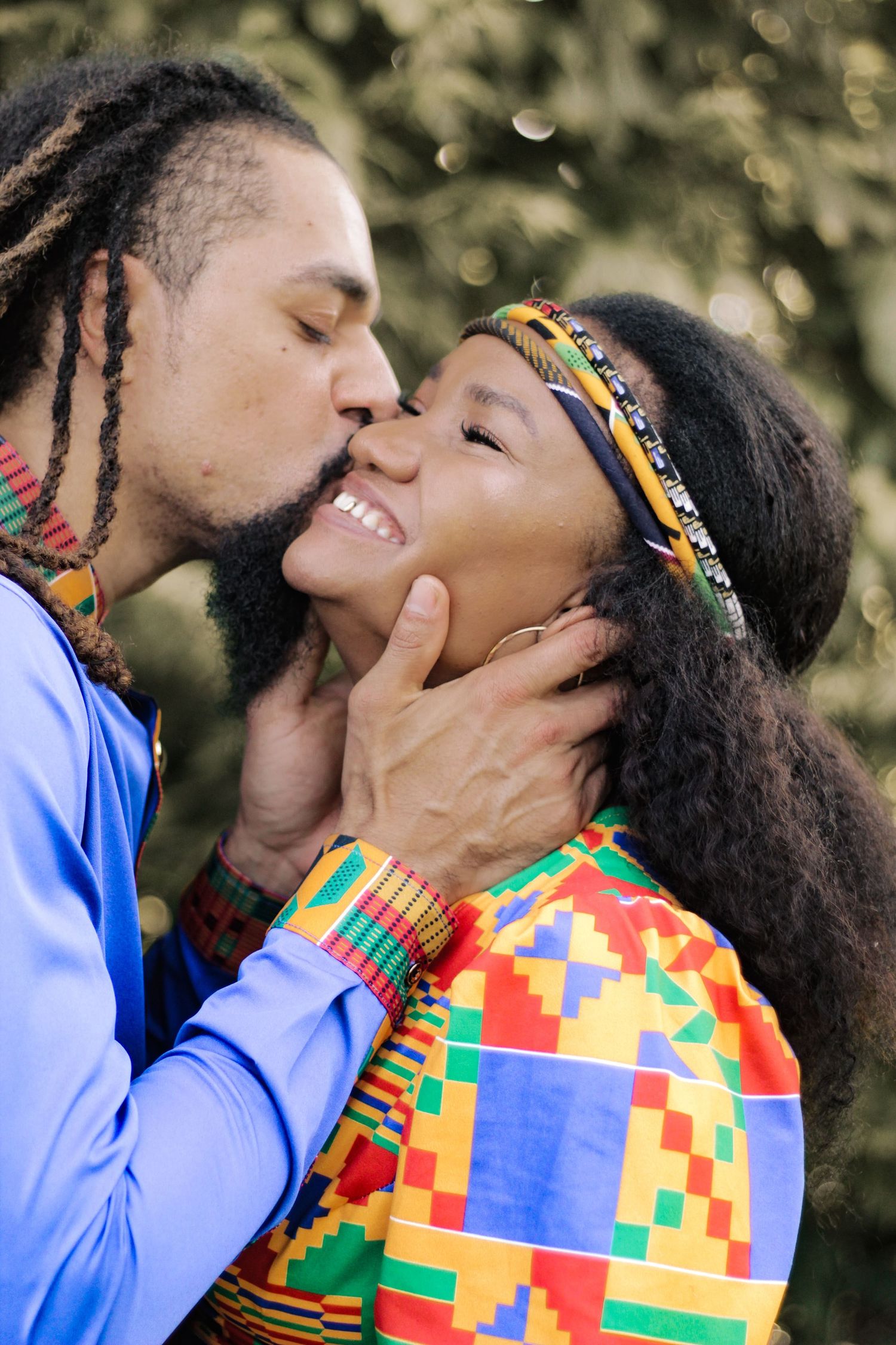 A tender moment between a couple wearing vibrant African-print clothing.
