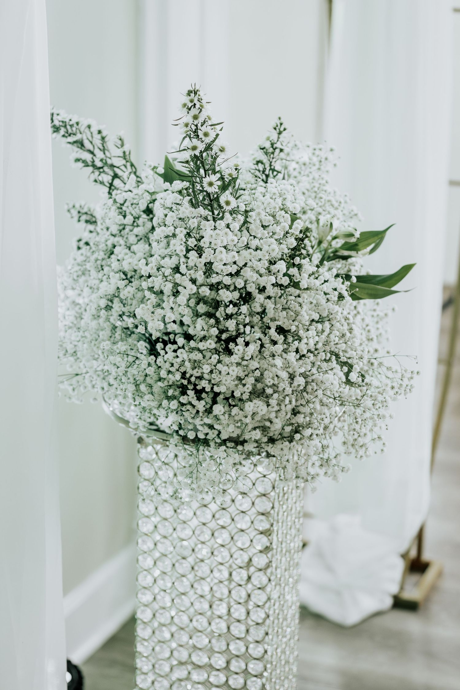 Close-up of baby's breath floral arrangement in a textured crystal cylinder vase.