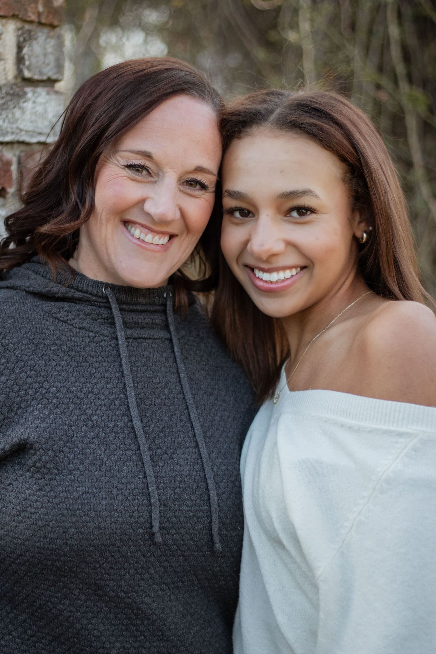 Close-up portrait of two friends wearing casual tops against a natural background.