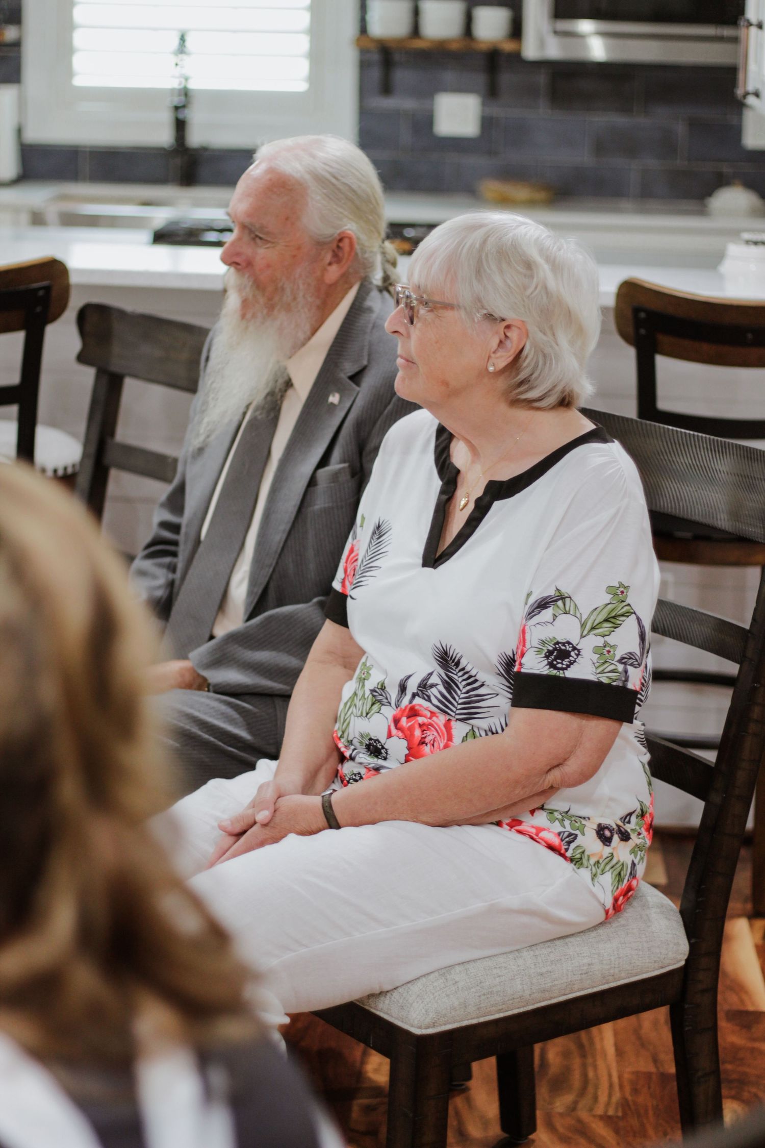 Wedding guests seated in wooden chairs watching ceremony proceedings.