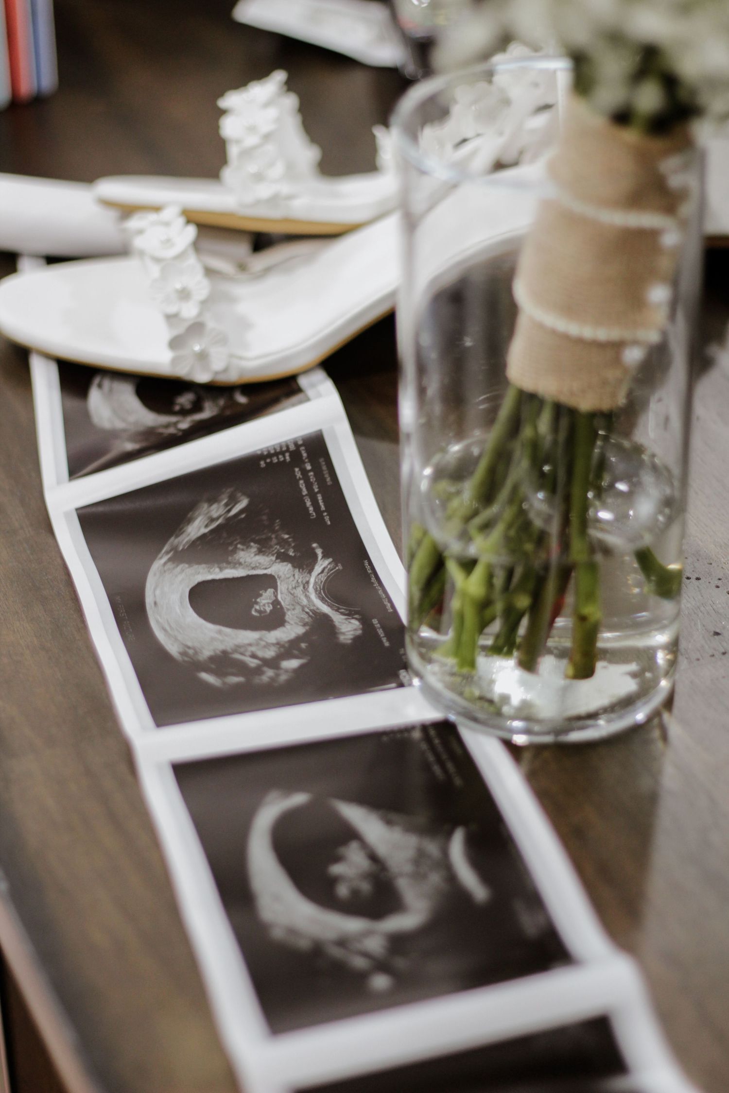 Black and white photos displayed with asparagus stems in glass vases on wooden table.
