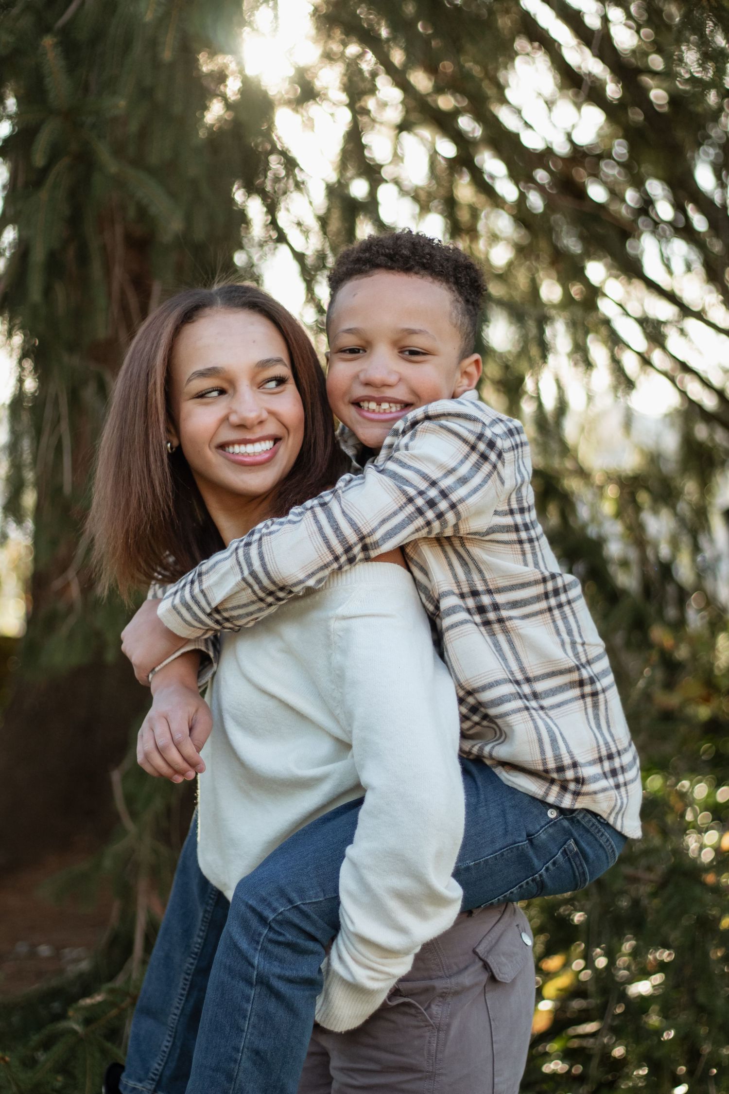 Candid outdoor portrait of parent and child sharing a laughing piggyback moment.