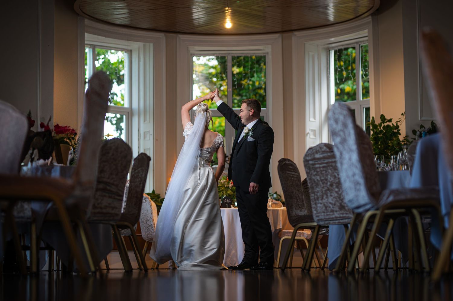 Bride and groom sharing a romantic toast in an elegant bay window ceremony room.