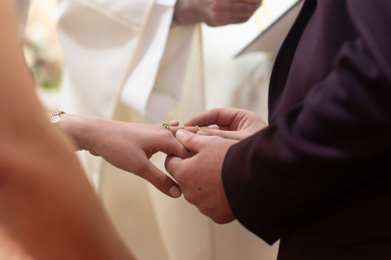 Groom placing a wedding ring on brides finger during a wedding ceremony.
