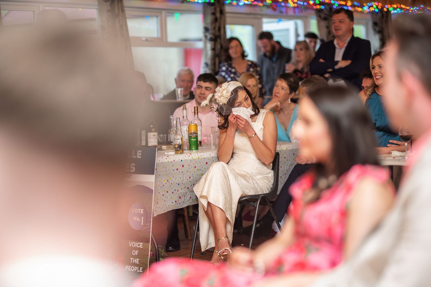 Guests laughing and enjoying themselves at a lively indoor wedding reception.