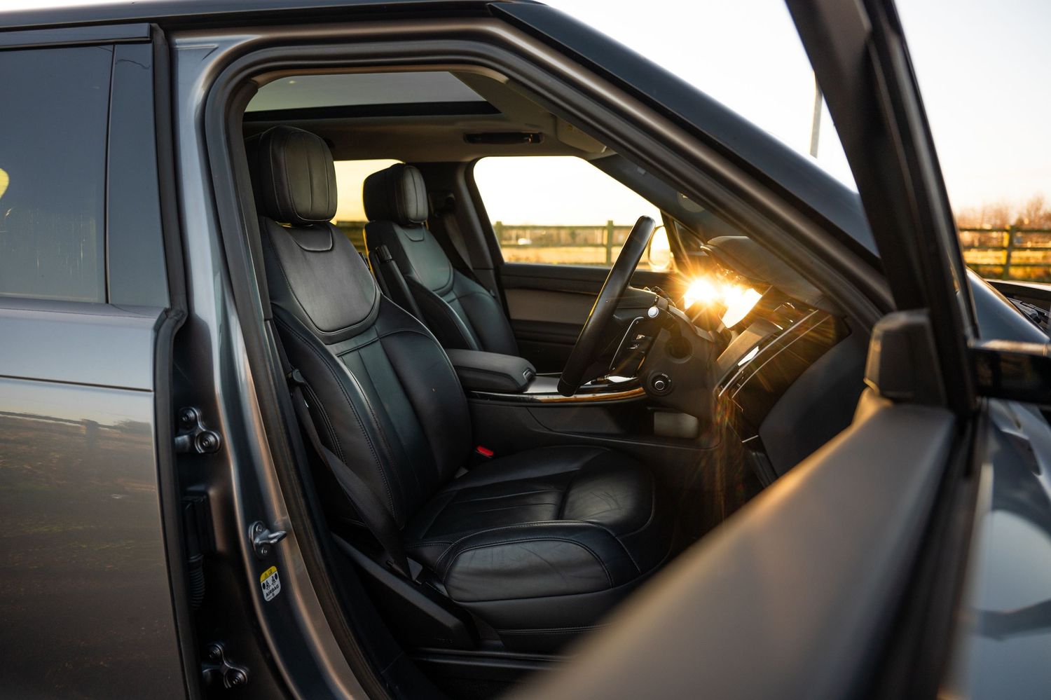 Luxury black leather interior of Range Rover SUV at golden sunset.