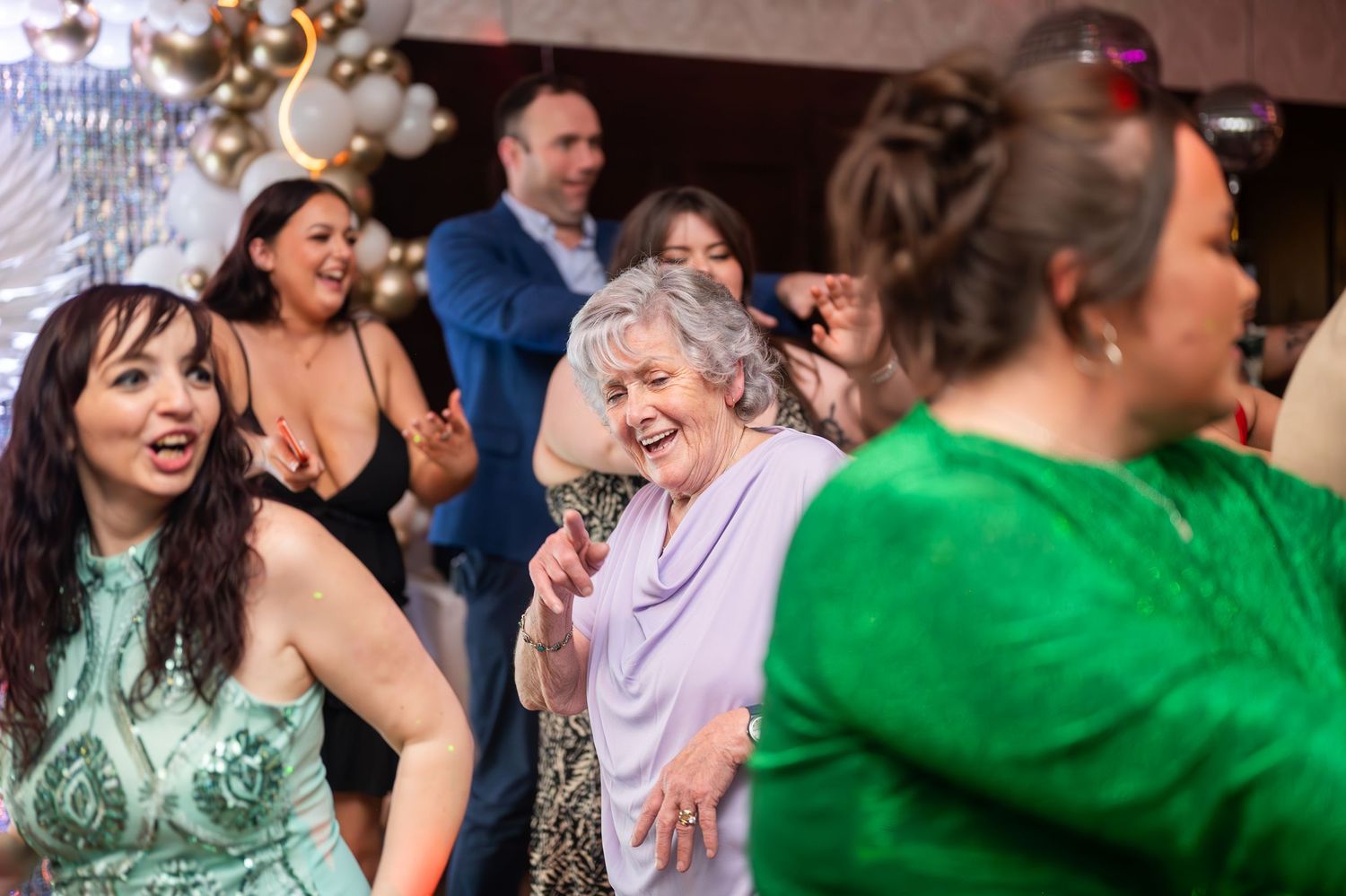 Group of women laughing and dancing joyfully at a formal party celebration.