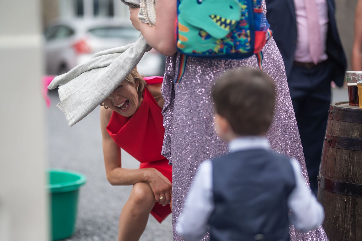 Woman in red dress bending down to interact with a young child at a wedding.