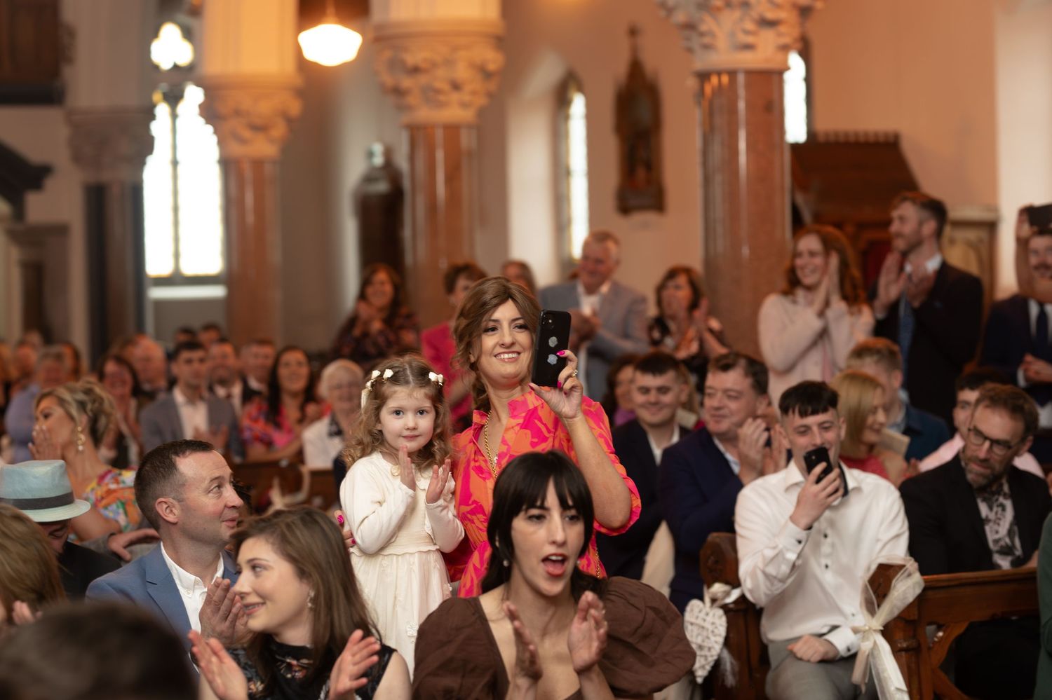 Guests clapping and celebrating inside a church during a wedding ceremony.