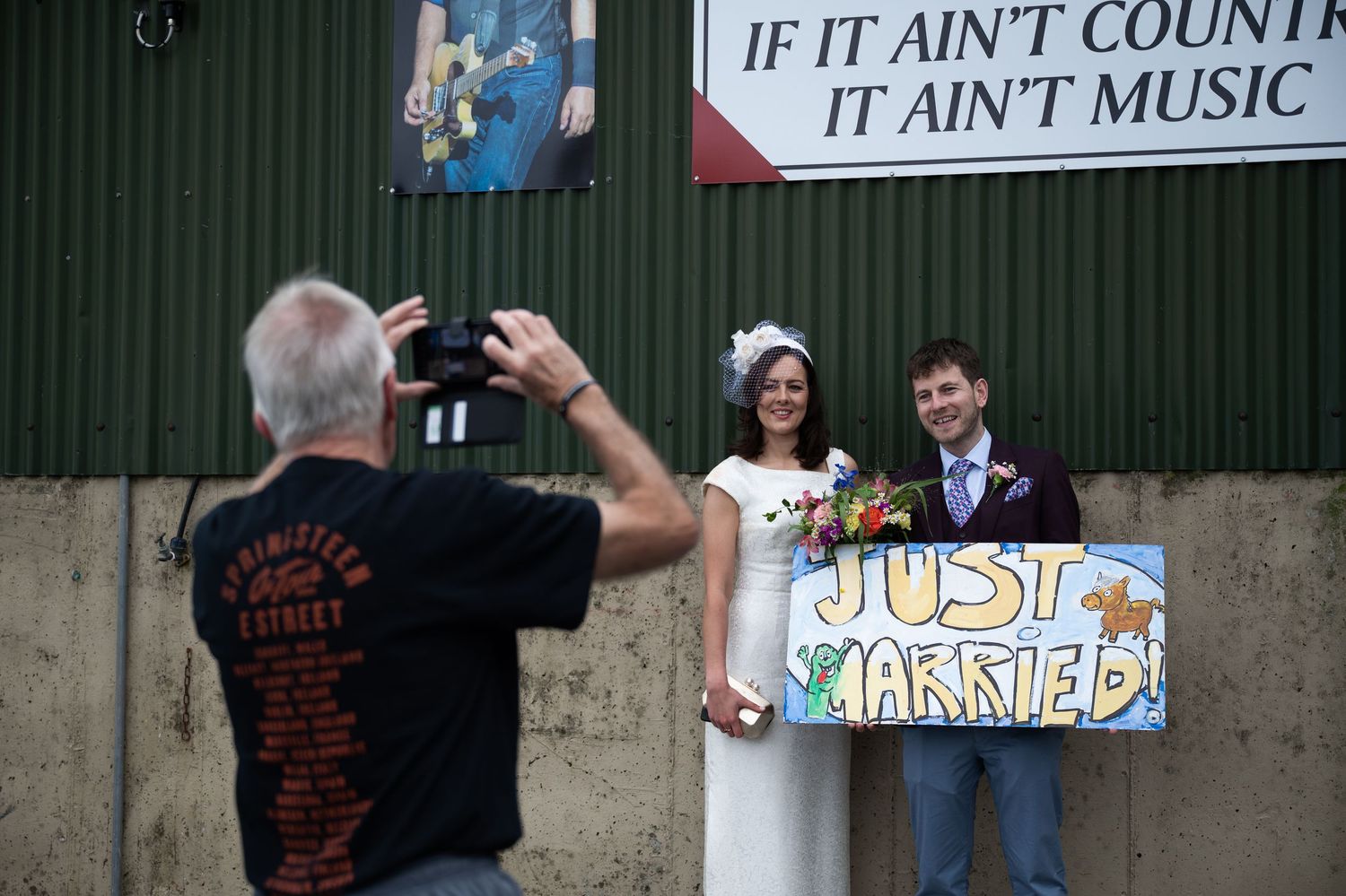 Newlyweds pose with a Just Married sign outside a country music venue.