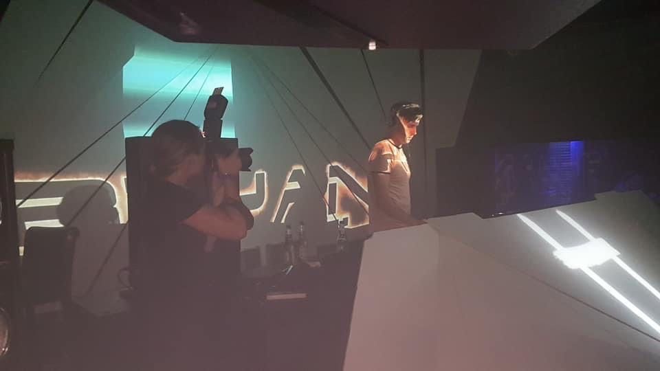 DJs performing at a nightclub with dramatic lighting and raised hand at a music event.