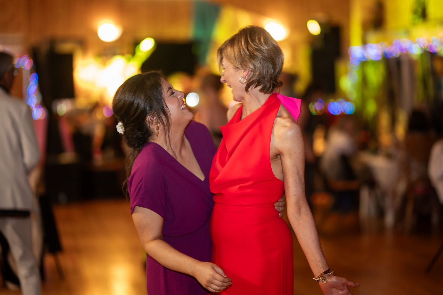 Two women sharing a joyful moment on the dance floor at a wedding reception.