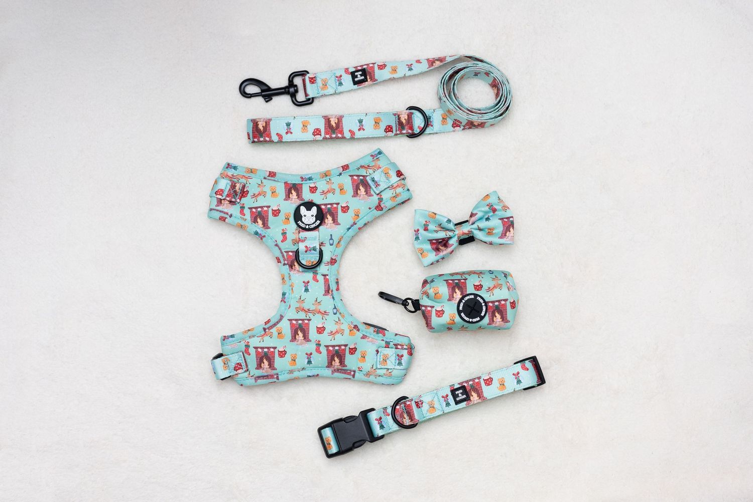 A light blue dog harness set with leash, bow tie, collar, and waste bag holder featuring colorful patterns.